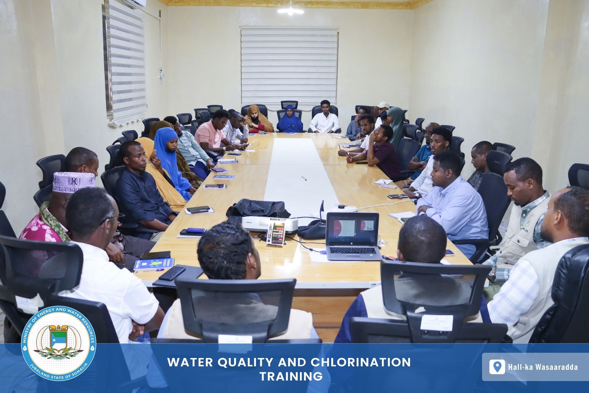 Group of people sitting around a conference table attending a water quality and chlorination training session.